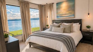 A bedroom with a large bed, a view of the lake, and a painting on the wall.