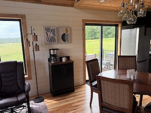 A cozy kitchen with a coffee maker, dining table, chairs, and artwork on the wall. - Just built 3-bedroom Scandinavian loft cottage near Lindstrom-Taylor's Falls (center city)