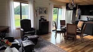 Un salón amplio con un ventanal grande, un conjunto de asientos cómodos y una cocina moderna.