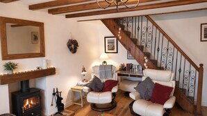 Una sala acogedora con chimenea, sillones de cuero, una escalera de madera y una estantería.