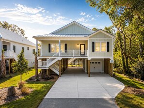 Ein zweistöckiges Haus mit überdachter Veranda, Garage und gepflegtem Rasen.
