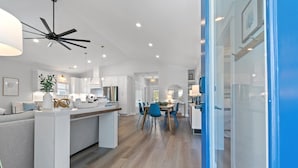 Una cocina moderna con una isla central, un comedor con sillas y un ventilador de techo.