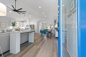 Eine moderne Küche mit einer zentralen Kochinsel, einem Essbereich mit Stühlen und einem Deckenventilator.
