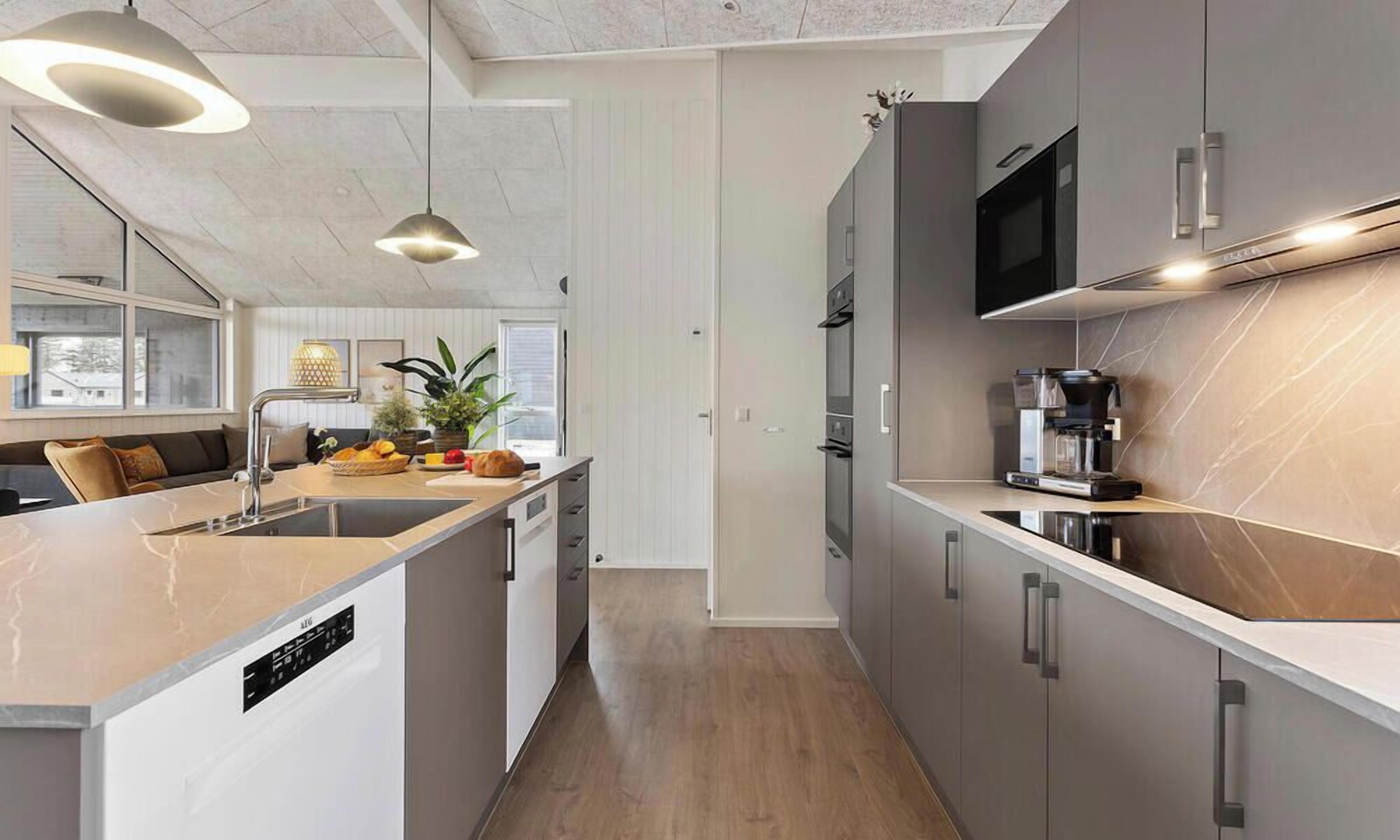 Una cocina moderna con una isla central, electrodomésticos integrados e iluminación colgante.