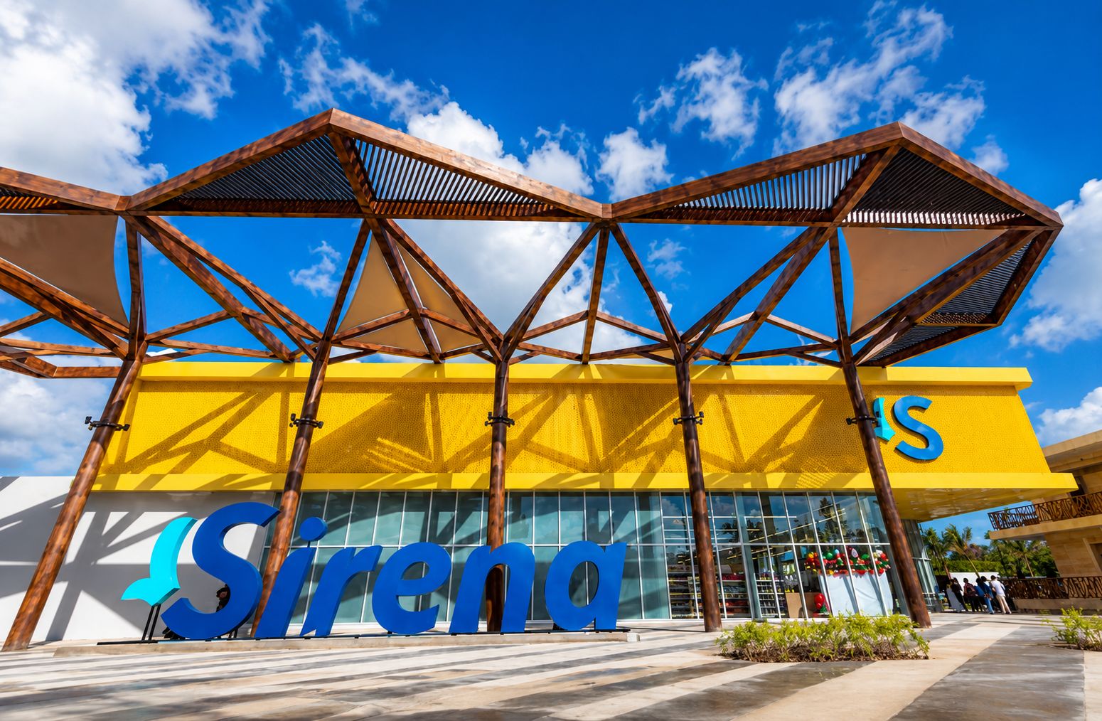 En modern byggnad med en framträdande skylt med texten ”Sirena”, kännetecknad av en geometrisk takkonstruktion och stora glasfönster.
