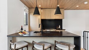 A modern kitchen with a central island, wooden cabinets, and pendant lighting. - Riverstone Retreat by Avantstay Shared Hot Tub + Mountain Views Walk to Gondola + San Miguel River Trail (Telluride)