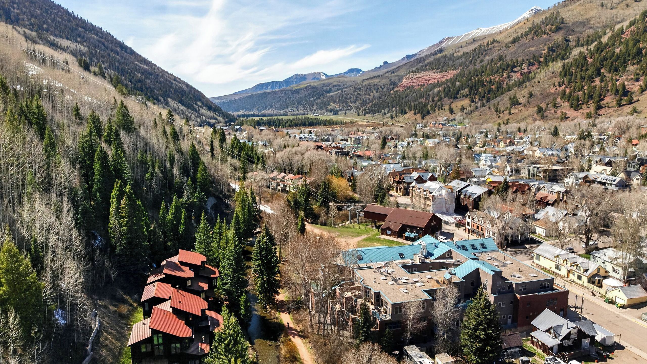 A town with a mix of residential and commercial buildings, surrounded by mountains and forests.