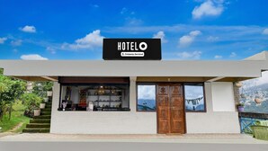 A hotel named 'HOTELO' with a company-serviced sign, a staircase leading to the entrance, and a view of the mountains in the background. - Deluxe Hotel O Ranka Gangtok (Gangtok)