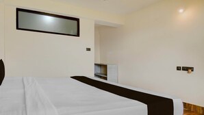 A hotel room with a bed, a mirror, a small table, and a wooden floor. - Deluxe Hotel O Ranka Gangtok (Gangtok)