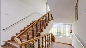 A staircase with wooden balusters and a handrail, leading to a landing with a window and a fire extinguisher.