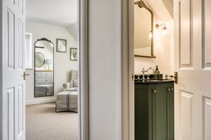 Un pasillo que da a un dormitorio con una cama, un aparador y un espejo.