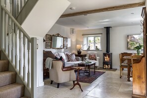 Ein großzügiges Wohnzimmer mit Kamin, einer Couch, einem Esstisch und einer Treppe.