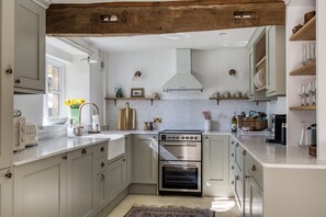 Eine Küche mit weißen Schränken, einem eingebauten Backofen und einem Holzbalken an der Decke.
