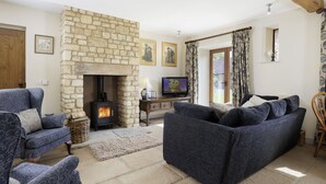 A cozy living room with a stone fireplace, comfortable seating, and a television. - Norton Subedge Barn -  Mickleton, Chipping Campden sleeps 6 guests (Mickleton)
