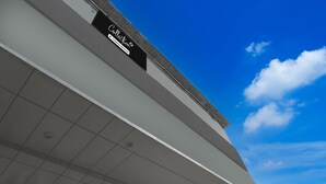 A modern building with a flat roof, a sign reading 'Collection,' and a clear blue sky with clouds. - Super Collection O Sector 18 Metro Station (Noida)