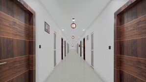 A long, narrow hallway with wooden paneling on the walls, numbered doors, and a series of lights on the ceiling. - Super Collection O Sector 18 Metro Station (Noida)