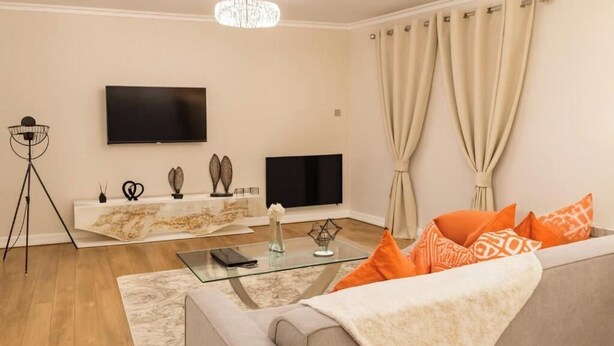Ein modernes Wohnzimmer mit einer Couch, einem Fernseher und einem Glastisch.