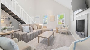 A spacious living room with a staircase, a fireplace, and a large TV. - Newly Renovated VB Retreat Comfort Space Home (Virginia Beach)