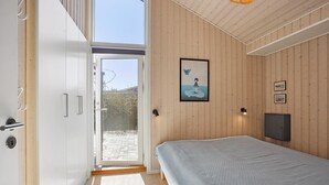 Ein Schlafzimmer mit Bett, einer Tür zu einem Außenbereich, einer Wandleuchte und einem gerahmten Bild.
