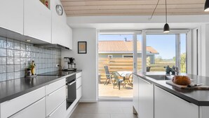 Eine moderne Küche mit einer Kaffeemaschine, einem Spülbecken und Blick ins Freie.