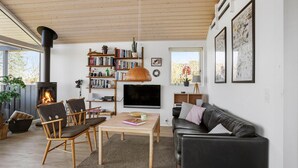 Ein gemütliches Wohnzimmer mit Kamin, Bücherregalen, einem Fernseher und einer komfortablen Sitzecke.