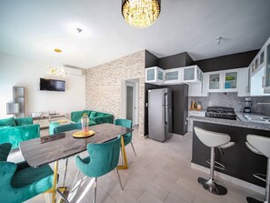 A modern kitchen with a refrigerator, stove, and bar stools. - 8BR Private Villa in Sosúa - 2 Mins From Nightlife (Sosúa)