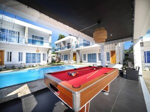 A pool table in a modern outdoor setting with a pool and a building with balconies. - 8BR Private Villa in Sosúa - 2 Mins From Nightlife (Sosúa)