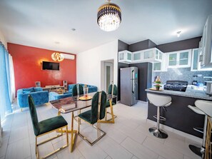 A modern kitchen with a refrigerator, stove, and bar stools. - 8BR Private Villa in Sosúa - 2 Mins From Nightlife (Sosúa)