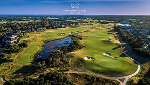Ein Luftbild des Sanctuary Lakes Golf Clubs mit einem See, Sandbunkern und einem gepflegten Golfplatz.