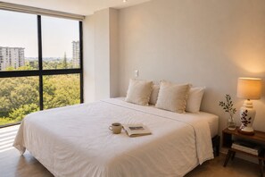 Ein Hotelzimmer mit einem großen Bett, einem Nachttisch mit Lampe, einem Fenster mit Blick auf die Stadt und einem Buch auf dem Bett.