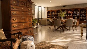 A spacious living area with a large wooden cabinet, a dining table with chairs, and a collection of decorative plates and vases. - 3BR · Country Club Guadalajara · cocina · rooftop bar · WiFi (guadalajara)