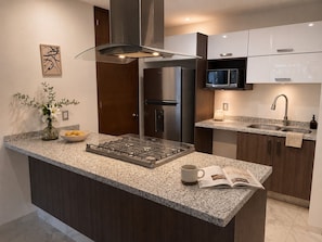 A modern kitchen with a central island, stainless steel appliances, and a granite countertop. - Japandi en Country Club GDL · caminable · rooftop · limpieza diaria (guadalajara)