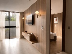 Une salle de bain moderne avec un meuble-lavabo en bois, un téléviseur fixé au mur et une grande fenêtre avec des rideaux.