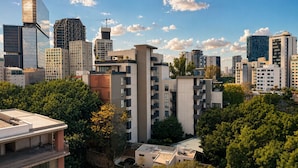 Eine Stadtansicht mit modernen Gebäuden, darunter ein markanter Glasturm und ein Gebäude mit einer ungewöhnlichen, geometrischen Fassade.