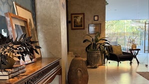 Ein Zimmer mit einer Holztische, einer großen Vase, einer Couch und einer Topfpflanze.