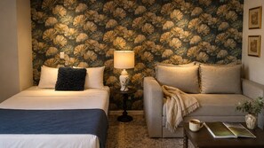 A room with a bed, a sofa, a nightstand with a lamp, and a small table with a book and a cup. - Premier Junior suite · rooftop bar · Country Club · limpieza diaria (guadalajara)
