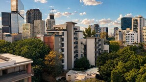 Un paisaje urbano con edificios modernos, incluyendo un llamativo rascacielos de vidrio y un edificio con una fachada geométrica distintiva.