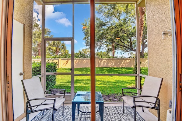 A glass door leading to an outdoor patio with two chairs and a small table. - Fantastic location , 3BD/2BT Condo with garage,patio and pool in Gated community (Sarasota)