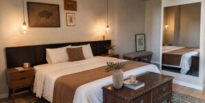 A bedroom with a bed, bedside tables, a nightstand, a mirror, and a vase with a book. - Estudio King · rooftop bar · Country Club GDL · limpieza diaria (guadalajara)