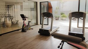 Ein Fitnessraum mit Laufbändern, einem Ergometer und einer Bank.