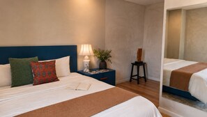 A hotel room with a bed, a nightstand, a lamp, a plant, and a chair. - Estudio · vistas + rooftop · Country Club GDL · limpieza diaria (guadalajara)