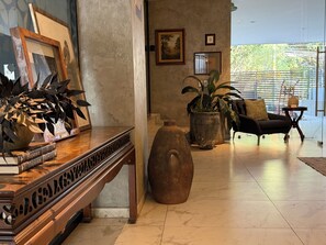 A room with a wooden console table, a large vase, a sofa, and a potted plant. - Estudio Premier · vistas · Country Club GDL · limpieza diaria (guadalajara)