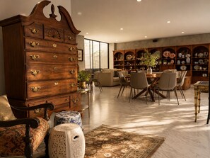 A spacious living area with a large wooden cabinet, a dining table with chairs, and a collection of decorative plates and vases. - Junior suite · vistas + rooftop · Country Club · limpieza diaria (guadalajara)
