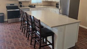 Une cuisine dotée d’un îlot central, de tabourets de bar, d’un réfrigérateur et d’un four à micro-ondes.