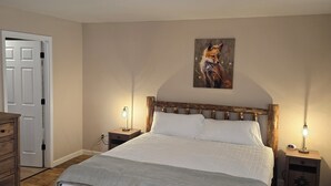 Une chambre avec un lit en bois, un tableau au mur et deux lampes de chevet.