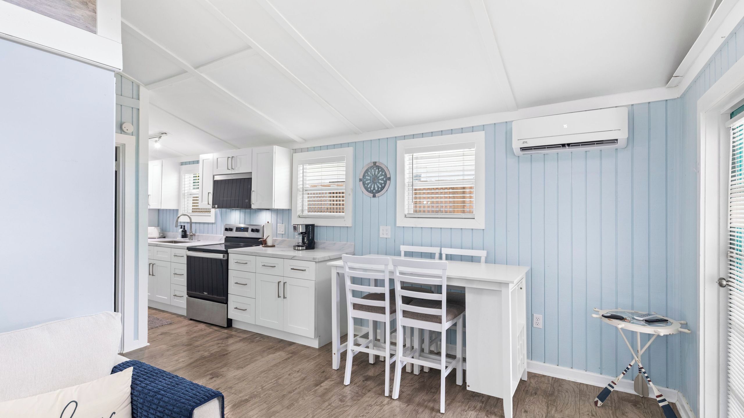 A kitchen with white cabinets, a stove, and a dining area with a white table and chairs.