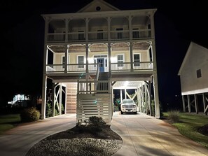 A two-story building with a covered porch, a driveway, and a vehicle parked inside. - Bee by the Sea, 5 BR house 1 minute to the beach, private road near restaurants (Oak Island)