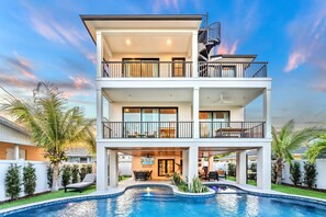 Ein zweigeschossiges Wohnhaus mit Swimmingpool, Sitzgelegenheiten im Freien und einer Treppe.