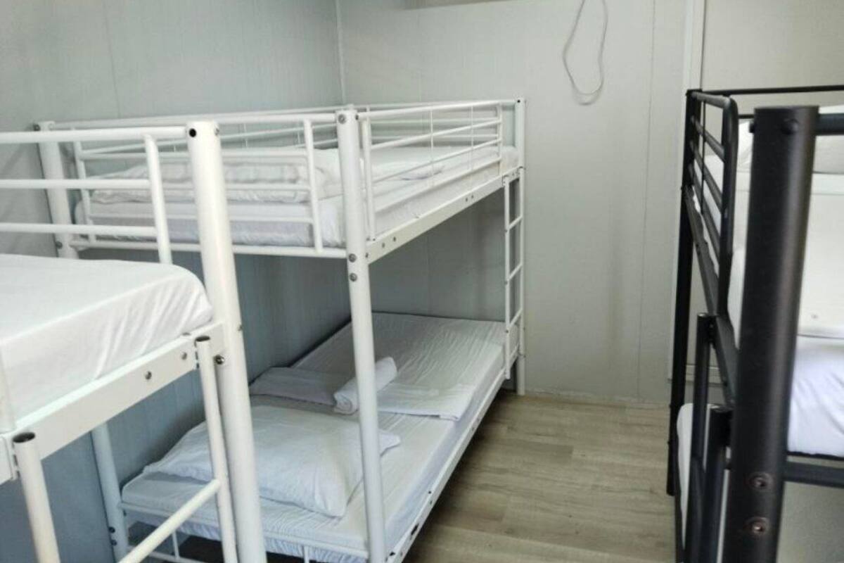 A bunk bed room with a white metal frame, a wooden floor, and a white wall.