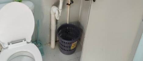 A bathroom with a toilet, sink, and a trash bin.